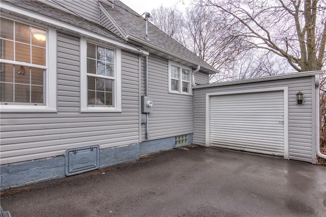 view of side of property featuring driveway and a shingled roof