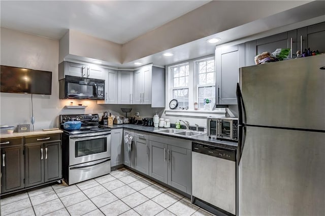 kitchen featuring light tile patterned floors, dark countertops, recessed lighting, appliances with stainless steel finishes, and a sink