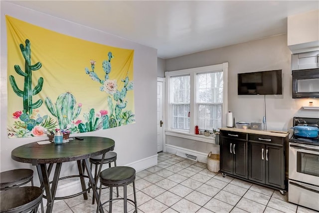 kitchen with light tile patterned floors, baseboards, visible vents, stainless steel electric stove, and black microwave