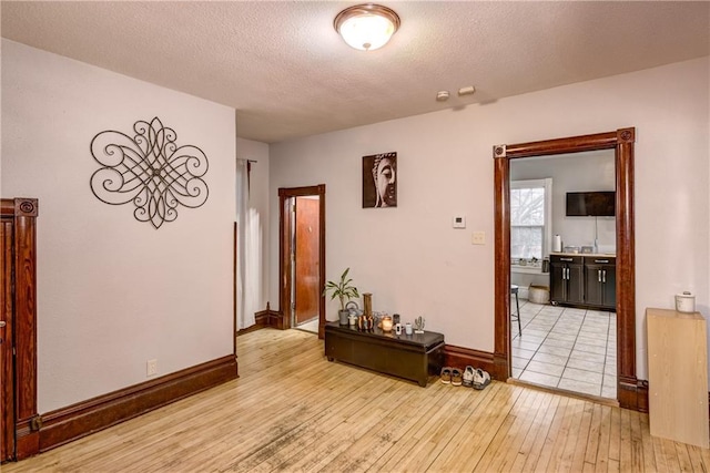 corridor with a textured ceiling, baseboards, and hardwood / wood-style floors