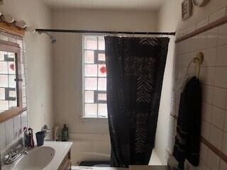 bathroom featuring curtained shower, vanity, and tile walls