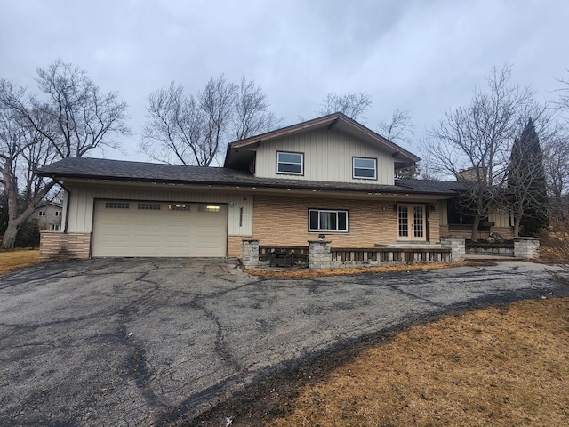 view of front of home featuring aphalt driveway, french doors, stone siding, and an attached garage