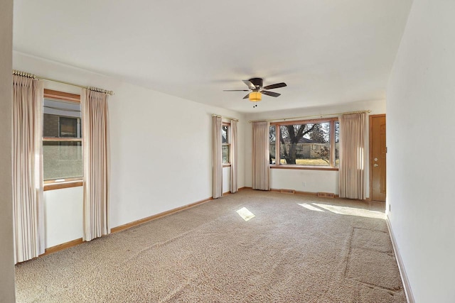 spare room featuring a ceiling fan, light colored carpet, and baseboards