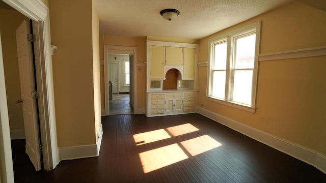 unfurnished room with dark wood-style floors, a textured ceiling, and baseboards