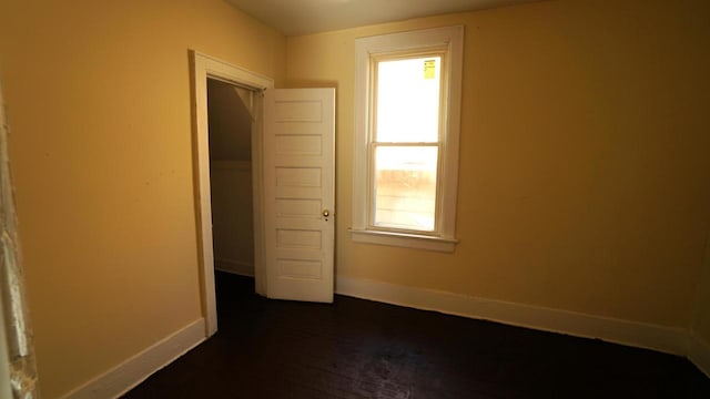 unfurnished bedroom with dark wood-style flooring and baseboards