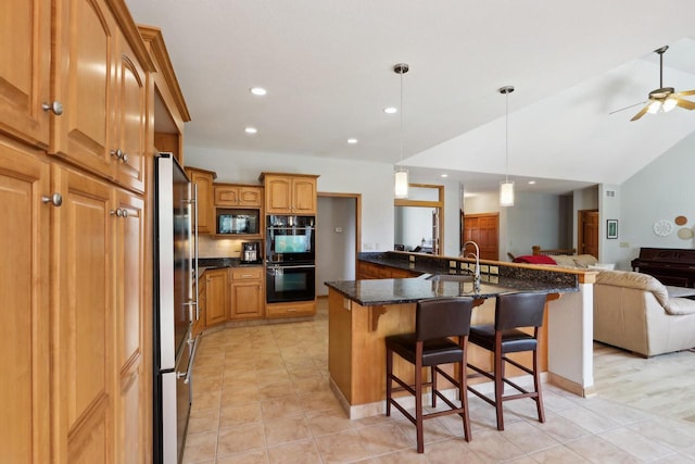 kitchen featuring black appliances, a breakfast bar, a ceiling fan, a sink, and open floor plan