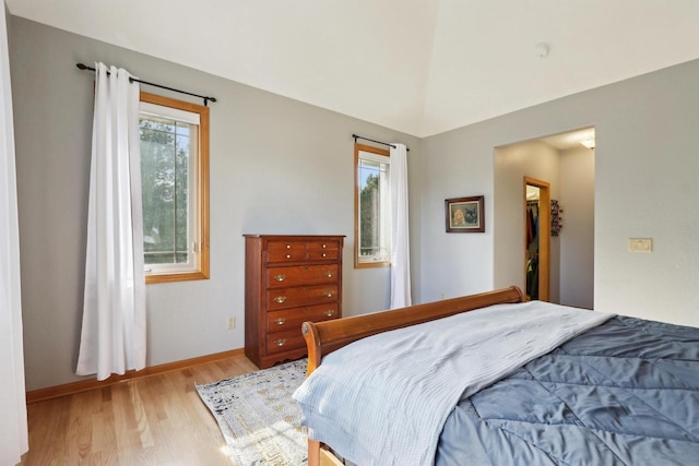 bedroom featuring baseboards, light wood-style floors, and vaulted ceiling