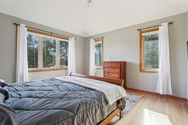 bedroom featuring light wood finished floors, multiple windows, and baseboards