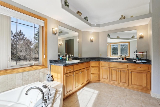 bathroom featuring tile patterned floors, a whirlpool tub, double vanity, and a sink