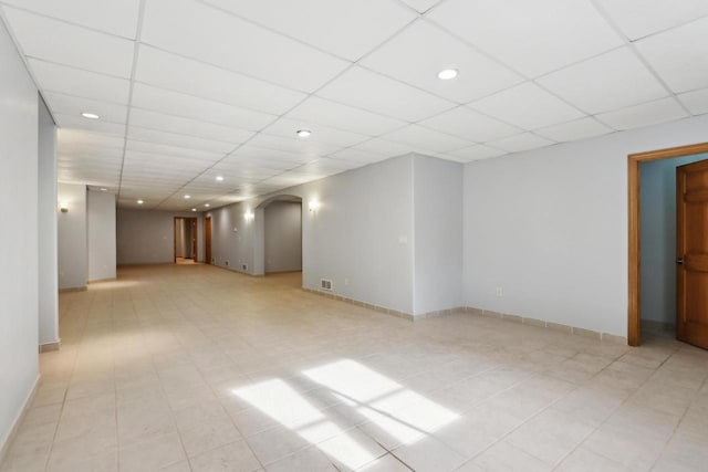 unfurnished room with visible vents, baseboards, recessed lighting, arched walkways, and a drop ceiling