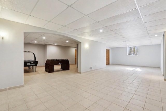 basement featuring visible vents, baseboards, recessed lighting, arched walkways, and a drop ceiling