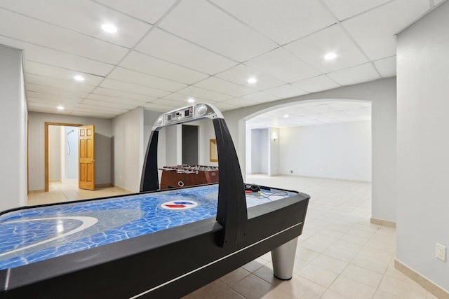 game room featuring arched walkways, a drop ceiling, recessed lighting, and baseboards