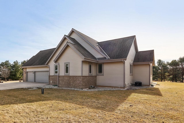 exterior space with an attached garage, a shingled roof, concrete driveway, a front lawn, and brick siding