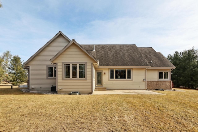 back of property featuring brick siding, a lawn, a shingled roof, and a patio