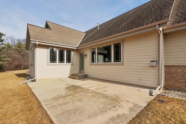 back of house featuring brick siding, roof with shingles, and a patio area