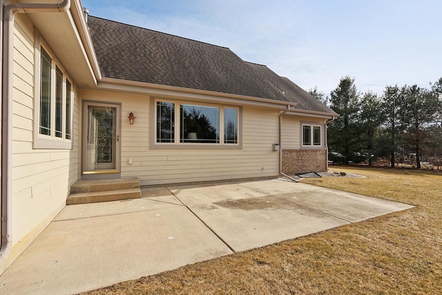 back of house featuring a patio area, a lawn, brick siding, and roof with shingles