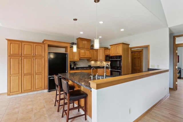 kitchen with tasteful backsplash, recessed lighting, a kitchen breakfast bar, black appliances, and a sink