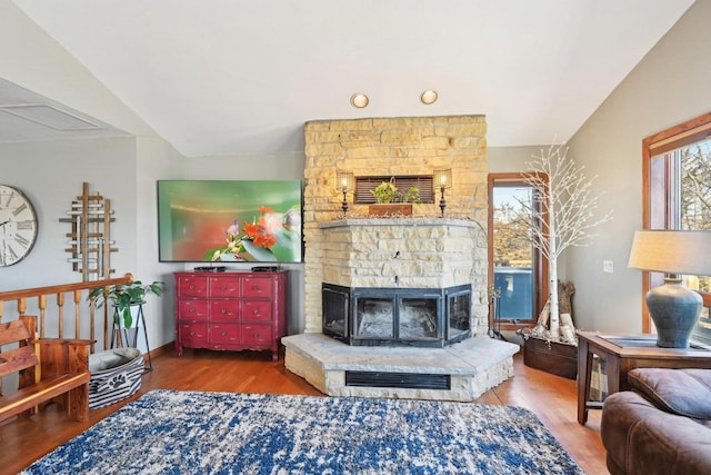 living area featuring vaulted ceiling, a large fireplace, and wood finished floors