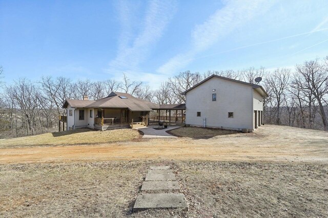 rear view of property featuring a porch and a chimney