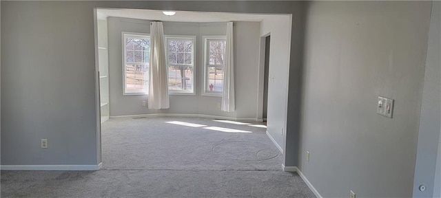 carpeted empty room featuring baseboards