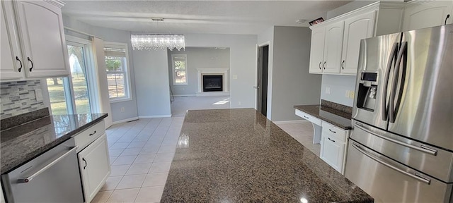 kitchen with dark stone countertops, light tile patterned floors, tasteful backsplash, and appliances with stainless steel finishes