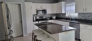 kitchen featuring dark countertops, tasteful backsplash, a center island, a breakfast bar area, and stainless steel appliances