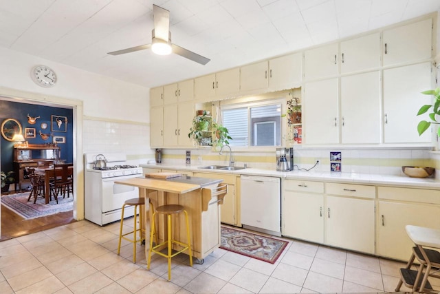 kitchen featuring white appliances, light tile patterned floors, ceiling fan, a sink, and light countertops