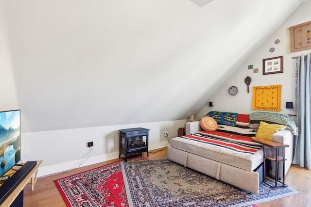 bedroom featuring baseboards, lofted ceiling, and wood finished floors