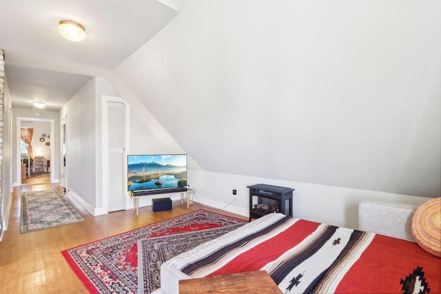 bedroom featuring vaulted ceiling, baseboards, and wood finished floors