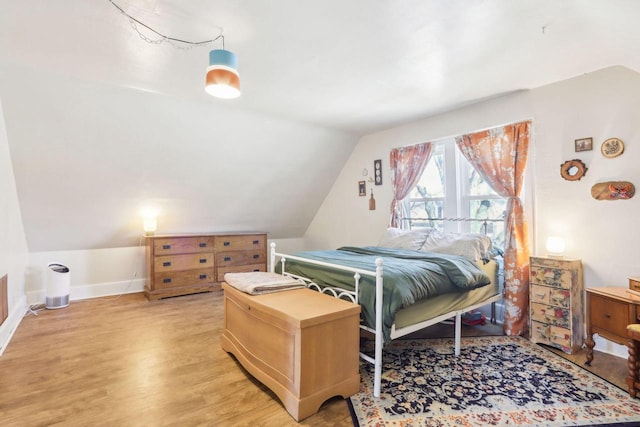 bedroom with vaulted ceiling, baseboards, and light wood-type flooring