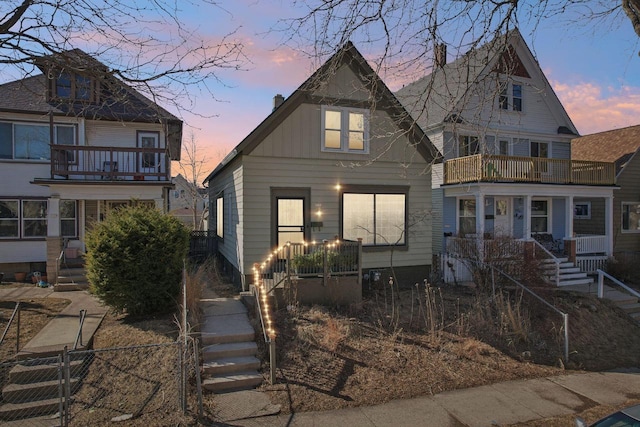 view of front of house featuring a porch, a balcony, fence, and a chimney