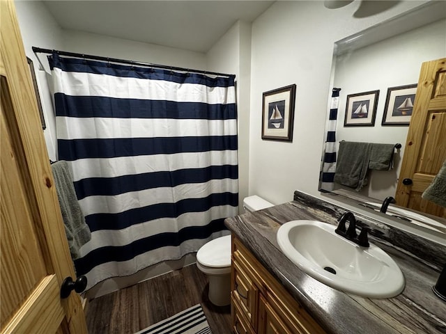 bathroom with toilet, vanity, a shower with curtain, and wood finished floors