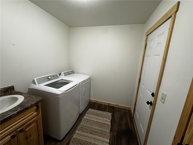 clothes washing area with baseboards, cabinet space, dark wood-style flooring, a sink, and washing machine and dryer