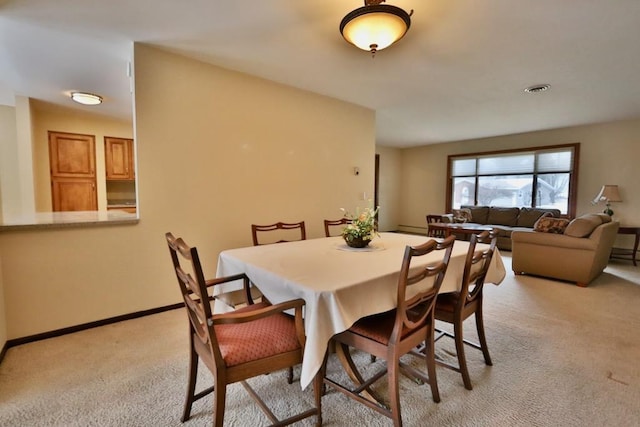 dining area featuring baseboards, visible vents, and light colored carpet