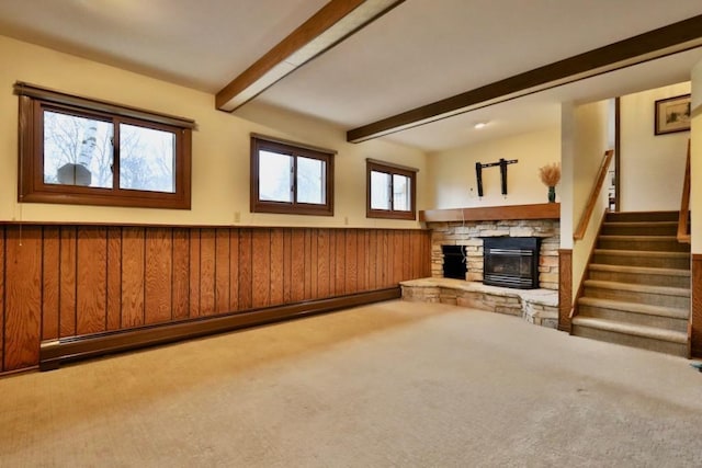 unfurnished living room with a baseboard heating unit, a wainscoted wall, a fireplace, stairs, and beam ceiling