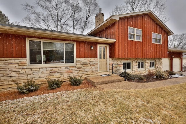 tri-level home with stone siding and a chimney