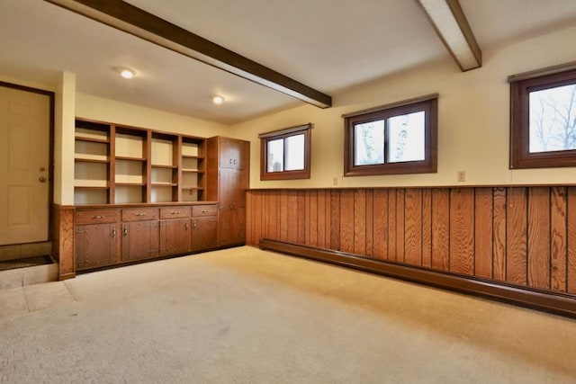 unfurnished room featuring a baseboard radiator, beam ceiling, a wainscoted wall, and a healthy amount of sunlight