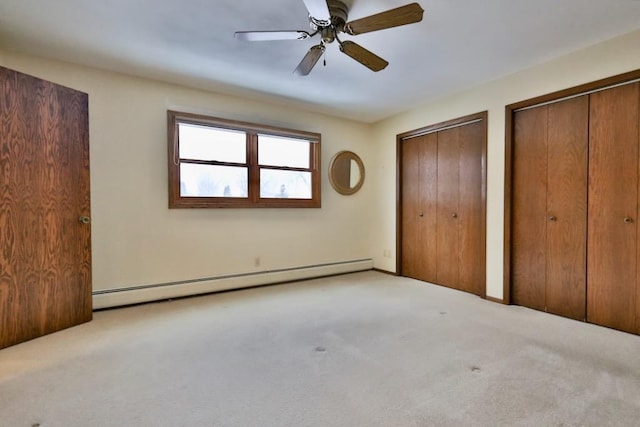 unfurnished bedroom featuring a ceiling fan, a baseboard heating unit, two closets, and carpet flooring