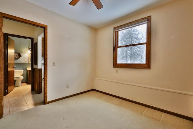 carpeted empty room featuring ceiling fan and baseboards