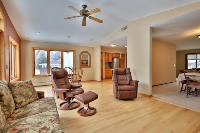 living area featuring lofted ceiling, light wood-type flooring, and plenty of natural light