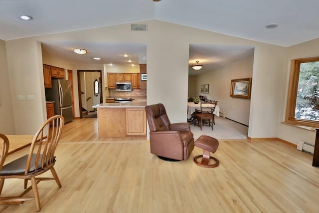 interior space with visible vents, lofted ceiling, open floor plan, stainless steel appliances, and light wood-style floors