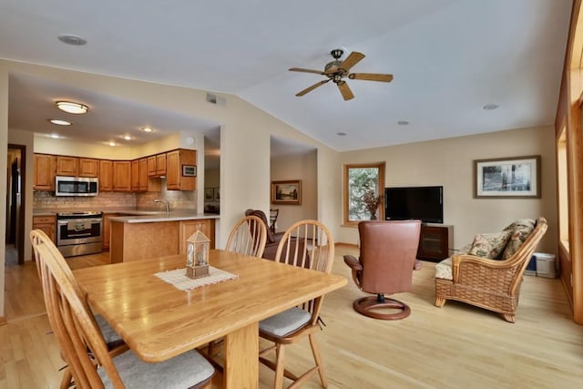 dining space featuring a ceiling fan, light wood-type flooring, visible vents, and vaulted ceiling