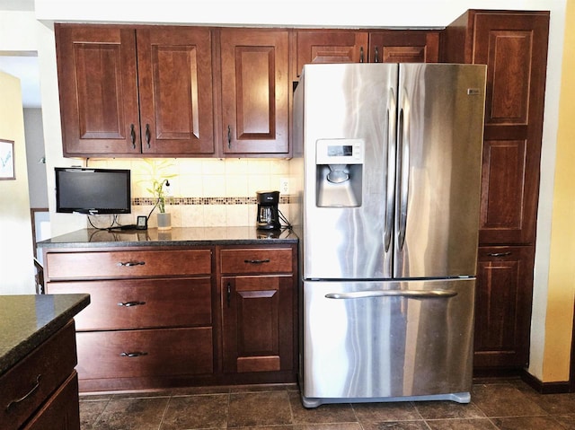 kitchen with dark stone counters, backsplash, and stainless steel fridge with ice dispenser