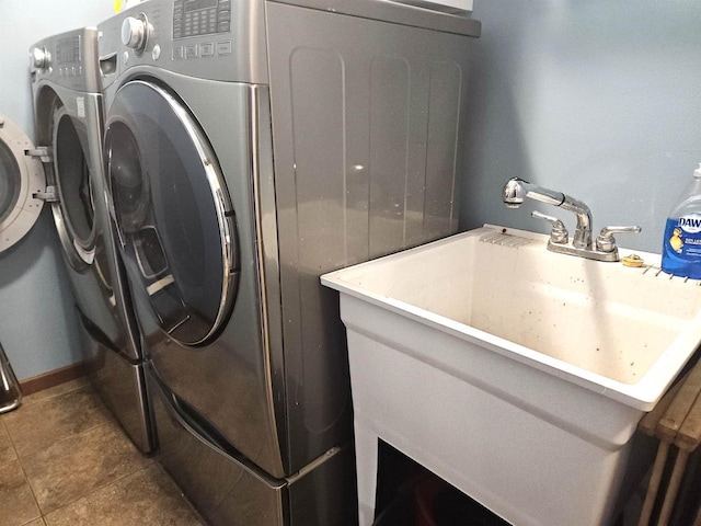 laundry area featuring tile patterned flooring, laundry area, a sink, baseboards, and washing machine and clothes dryer