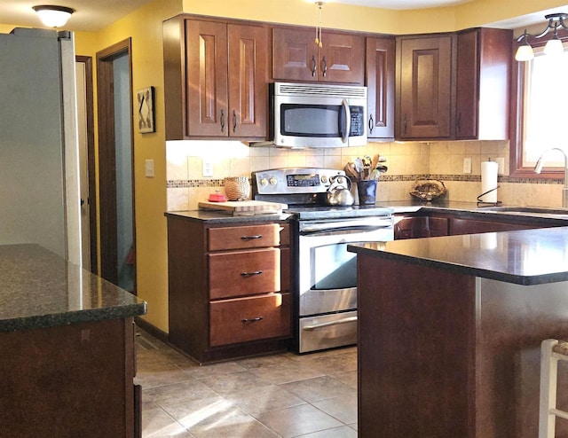 kitchen featuring a sink, appliances with stainless steel finishes, light tile patterned floors, and backsplash