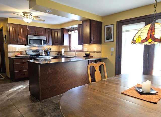 kitchen featuring a peninsula, dark brown cabinetry, appliances with stainless steel finishes, and decorative backsplash