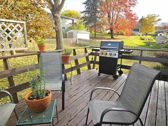 wooden terrace featuring an outbuilding, a yard, a grill, a shed, and a fenced backyard