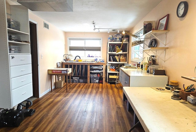 interior space featuring dark wood-type flooring, visible vents, baseboards, and a workshop area