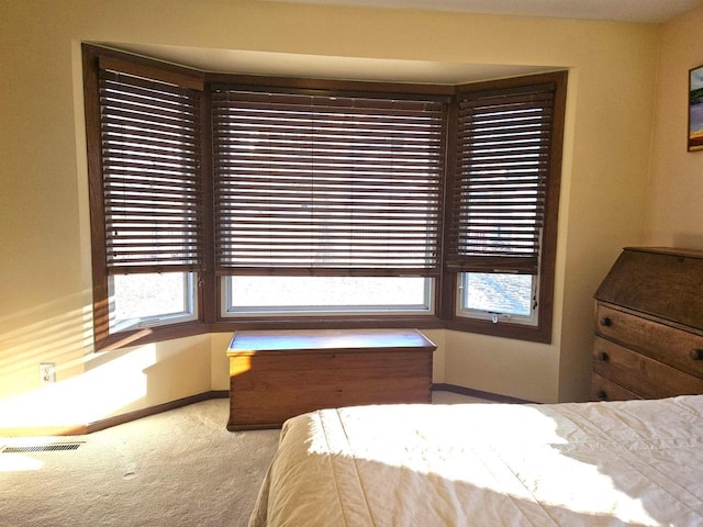 carpeted bedroom with visible vents, baseboards, and multiple windows