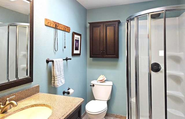 bathroom featuring a stall shower, baseboards, vanity, and toilet